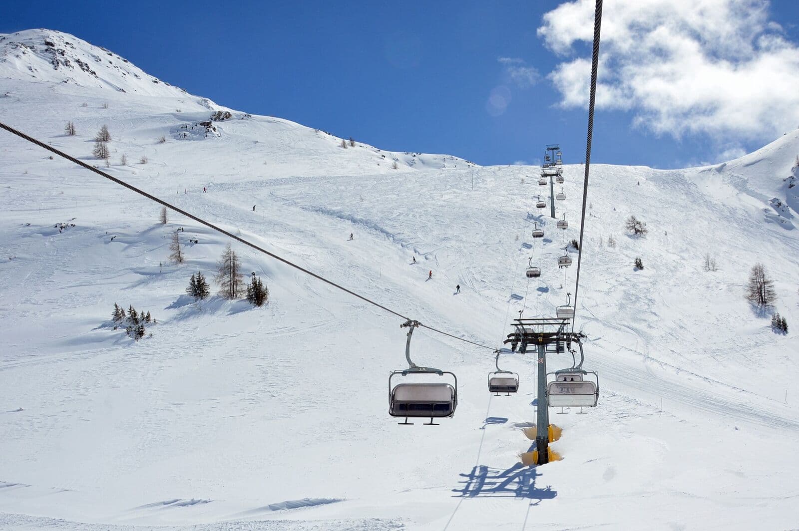 A chairlift rising over a sunny snowfield under a blue sky